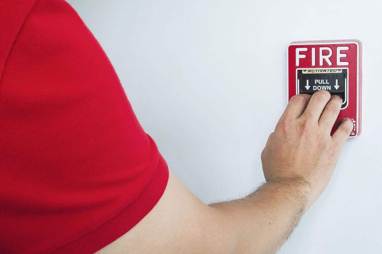 Hand reaching to activate a manual fire-alarm call point